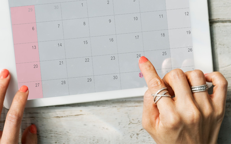 Mãos de mulher apontam para o dia 24 em um calendário sem especificação de mês ou de ano